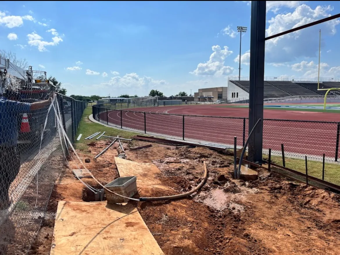 Horizontal directional drilling installation laying conduit at an athletic stadium track